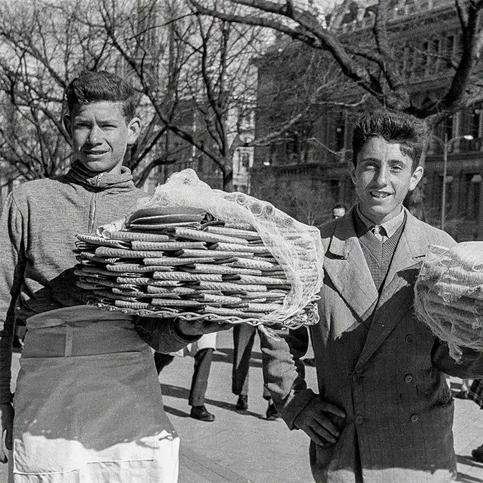 Fotografía en blanco y negro de dos jóvenes con pilas de piezas redondas en una calle
