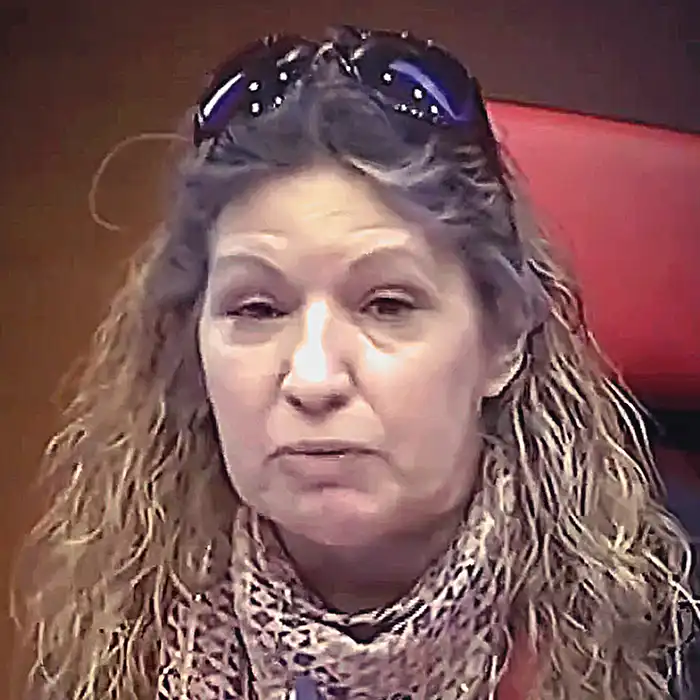 Retrato de una persona de cabello largo con gafas sobre la cabeza y pañuelo estampado
