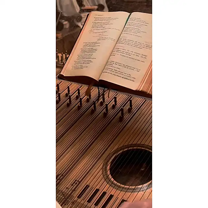 Instrumento de cuerda de madera junto a un libro abierto con versos impresos